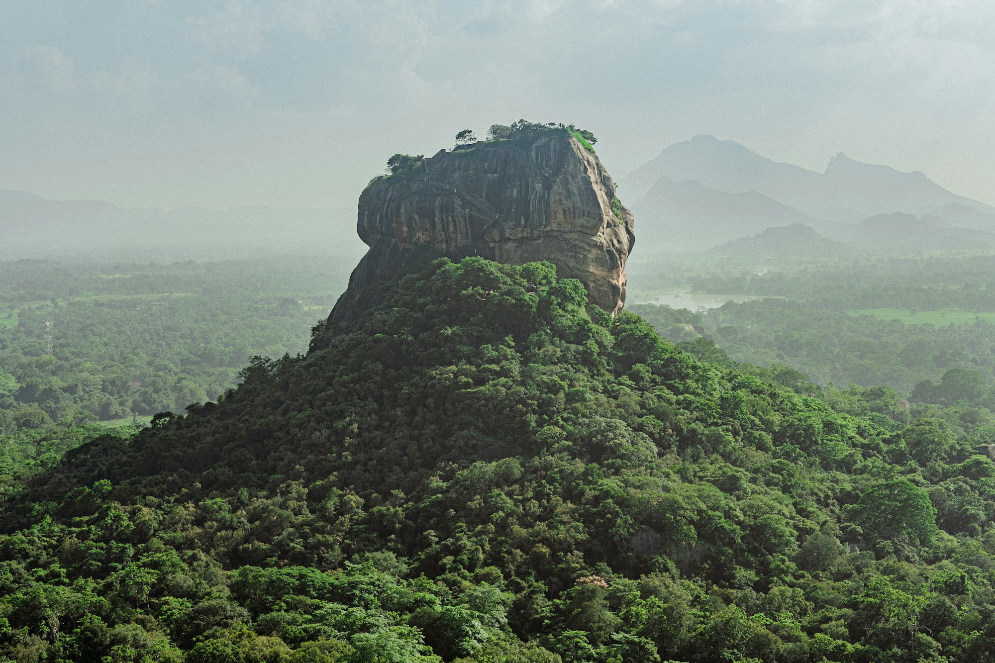 Sigiriya rock fortress rising above the forest in the morning mist, Sri Lanka